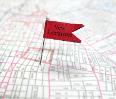 Map with a red "New Location" flag pinned on its surface.