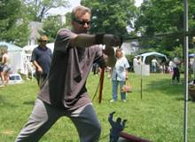 Sweetbriar Nature Center Wildlife and Craft Fair (June 11, 2005): Laoshi Laurince McElroy demonstrates the orthodox straight sword form and plays a little close to the Water Tiger School table.