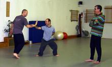 In the Kwoon, Perspectives on Tai Chi Push Hands (November 2007): With smiles all around, Laoshi Laurince McElroy (L) demonstrates Water Tiger Schools Single-Hand Moving Push Hands (Sticky Hands) exercise with Si-Hing Joel Valerio while Bob LaMantia observes.