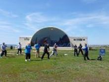 World Tai Chi & Qigong Day; Shorefront Park, Patchogue NY (April 27, 2013): Framed by the beautiful Shorefront Park Band Shell, Bill Donnelly (R), Green Cloud Kung Fu of Holbrook, helps people thread the nine-holed pearl with Silk Reeling (Chan Si) exercises.
