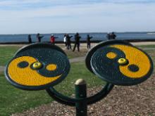 World Tai Chi & Qigong Day  Patchogue (April 25, 2015): Over the past year, Patchogue Parks & Recreation had a number of exercise stations installed in Shorefront Park. We couldnt resist taking this shot of the parks Tai Chi Spinners with Teresa Whites workshop in the background. Spinners usually have four wheels that can be turned in different directions with adjustable resistance. As an exercise, spinning works the flexibility and strength of the shoulders and other muscles that not only raise and lower the arms, but also provide shoulder stability.
