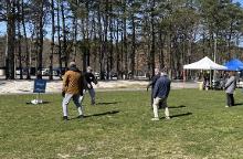A male workshop facilitator leads a small number of people in open-hand T'ai Chi Ch'uan fundamental drills.