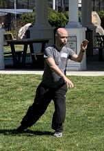 A man playing Wave Hands Like Clouds from an empty-hand T'ai Chi form.