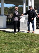 A political dignitary shaking hands with the event coordinator during the presentation of a proclamation.